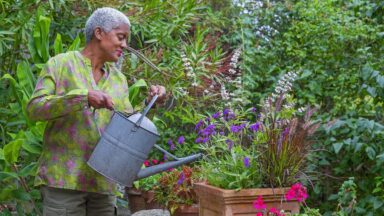 Arit Andersen geeft een pot vol zomerse planten, zoals verbena en pennisetum, water.