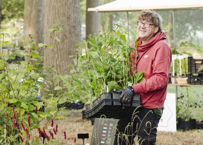 Kweker Pieter met een tray met planten in zijn handen.