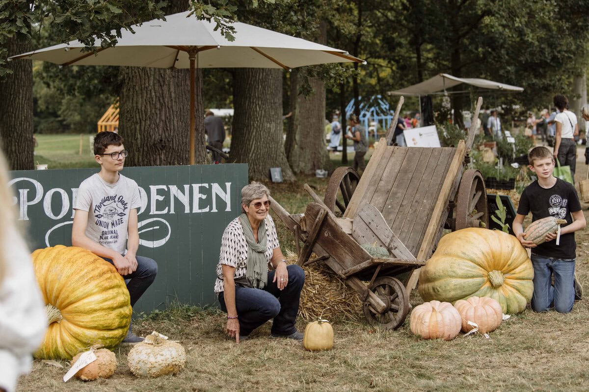 Mensen poseren bij pompoenen op de Ambachtelijke Plantenmarkt.