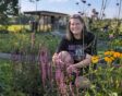 Hester zit geknield bij bloeiende planten in haar nieuwe border.