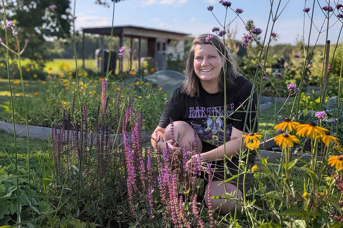 Hester zit geknield bij bloeiende planten in haar nieuwe border.