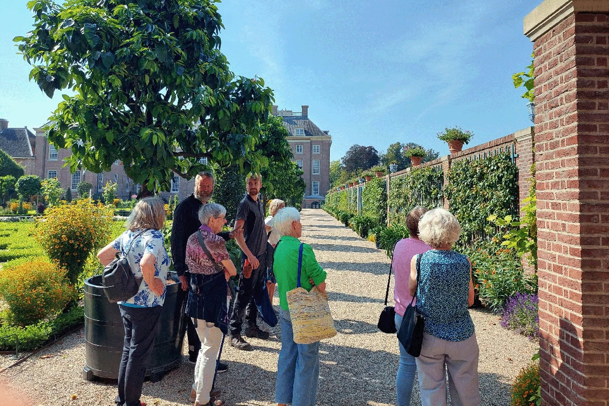 Groepje mensen volgt een rondleiding in de tuinen van Paleis Het Loo